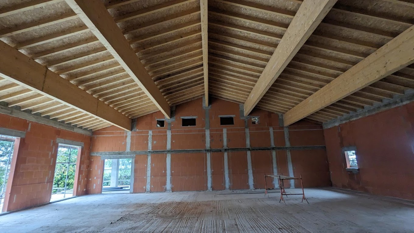Intérieur de maison en rénovation avec charpente bois apparente, murs en maçonnerie et travaux de gros œuvre réalisés par Bâtiment ECB